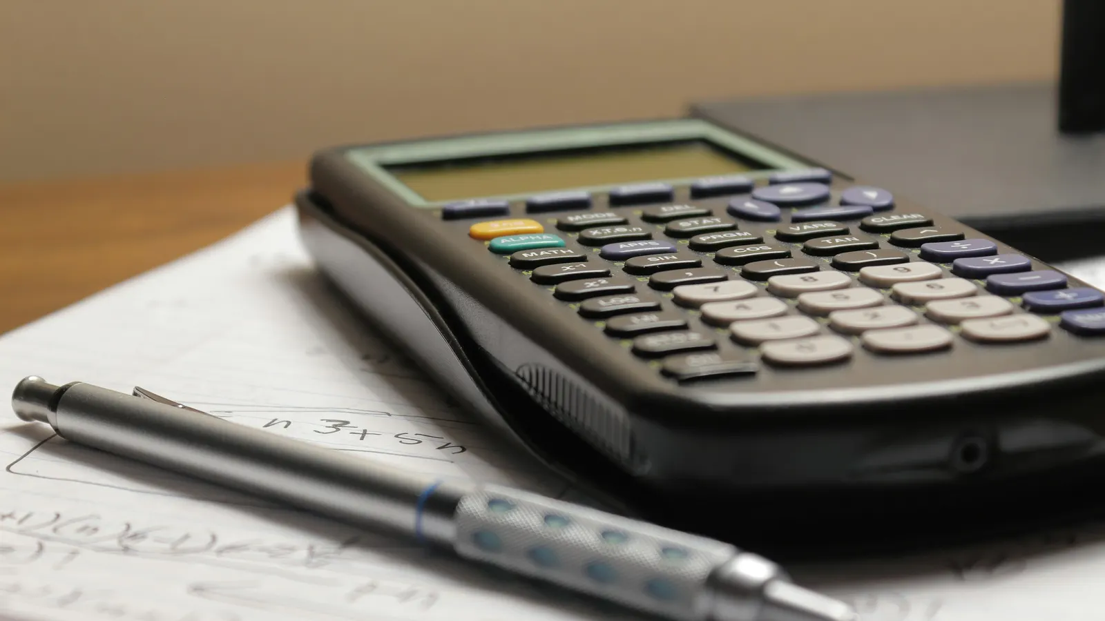 Calculator and pen on accounting papers, collecting unpaid invoices in Mexico